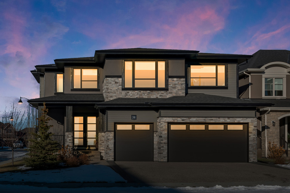 Inspiration for a contemporary brown two-story stucco and board and batten exterior home remodel in Calgary with a shingle roof and a black roof