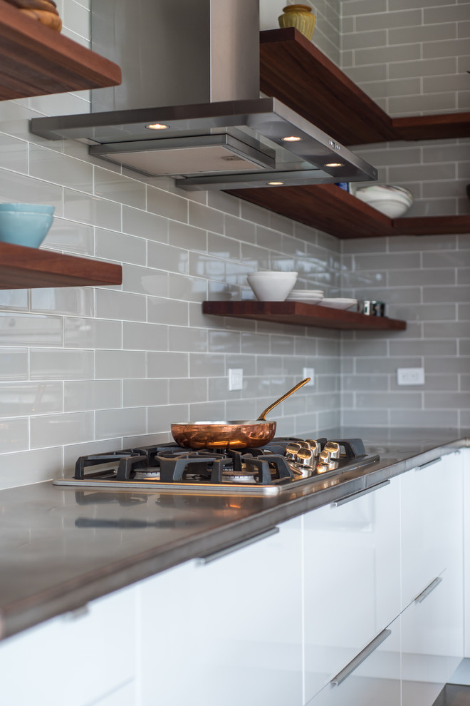 Small modern l-shaped open plan kitchen in Cleveland with an undermount sink, flat-panel cabinets, white cabinets, copper benchtops, grey splashback, porcelain splashback, stainless steel appliances, concrete floors, with island and grey floor.