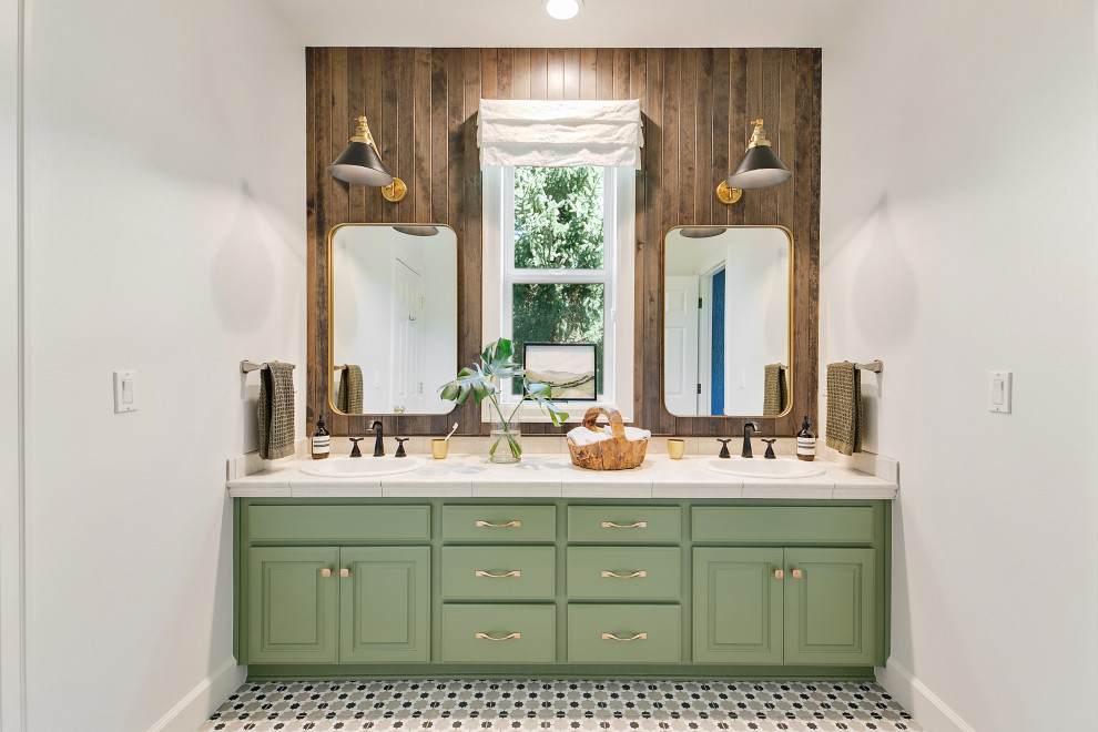 Photo of a large eclectic kids bathroom in Portland with raised-panel cabinets, green cabinets, an alcove shower, a one-piece toilet, brown tile, ceramic tile, white walls, porcelain floors, a drop-in sink, tile benchtops, multi-coloured floor, a hinged shower door, beige benchtops, an enclosed toilet, a double vanity, a built-in vanity and wood walls.
