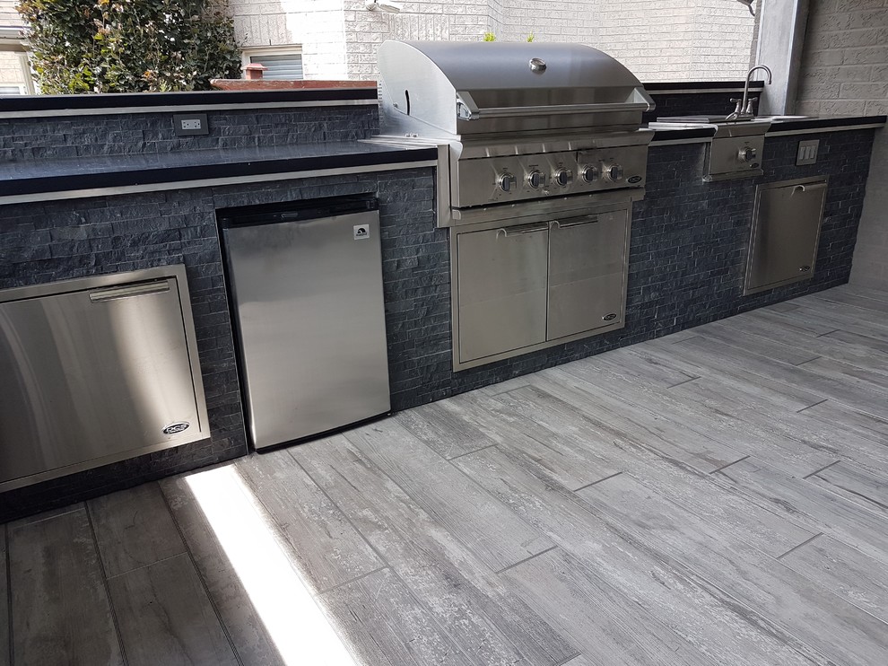 This is an example of a large transitional backyard patio in Toronto with an outdoor kitchen, concrete pavers and a roof extension.
