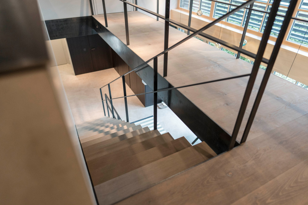 Inspiration for a contemporary wood staircase in Munich with metal railing.