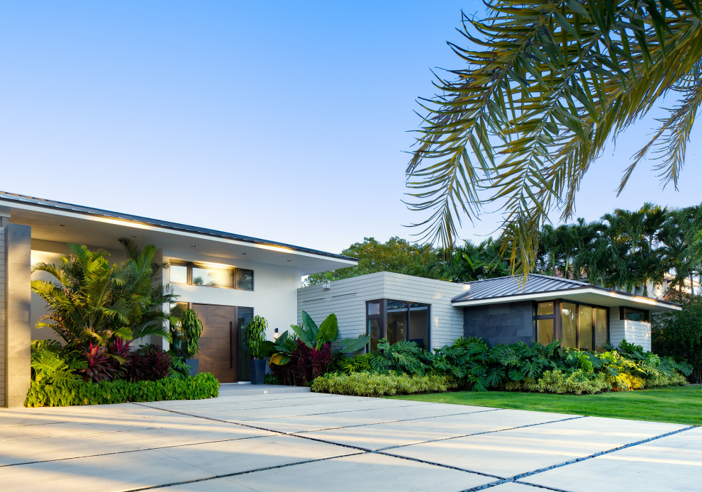 Geräumiges, Einstöckiges Modernes Einfamilienhaus mit Steinfassade, grauer Fassadenfarbe, Walmdach, Blechdach und schwarzem Dach in Miami