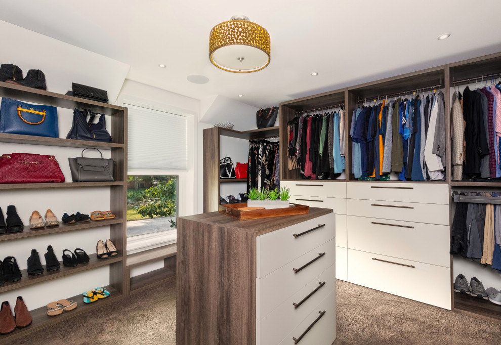 This is an example of a large contemporary gender-neutral storage and wardrobe in Detroit with flat-panel cabinets, light wood cabinets, carpet and beige floor.