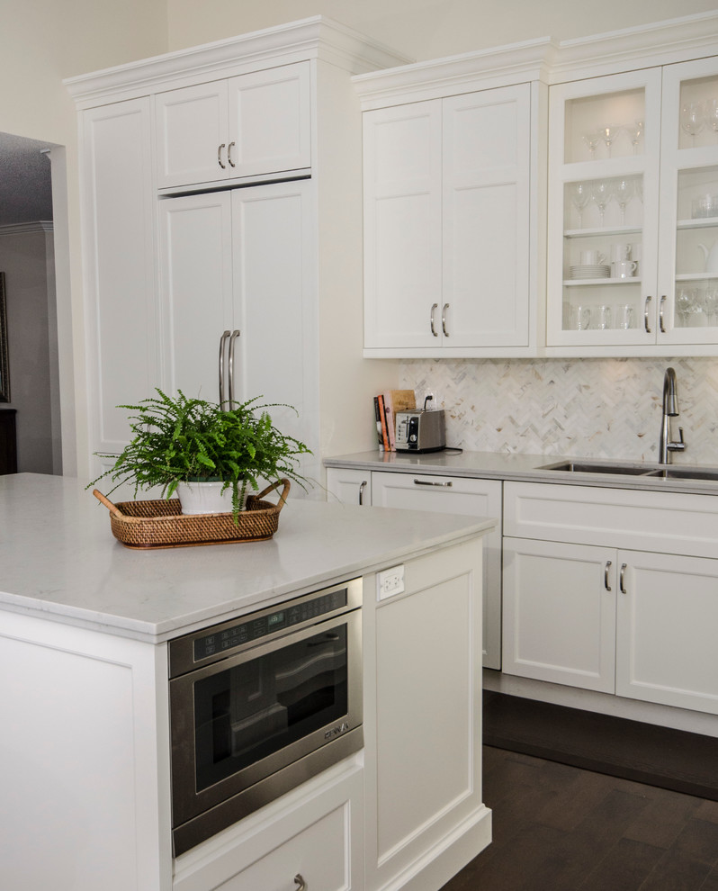 This is an example of a large traditional l-shaped eat-in kitchen in Toronto with an undermount sink, shaker cabinets, white cabinets, quartzite benchtops, white splashback, mosaic tile splashback, panelled appliances, dark hardwood floors and with island.