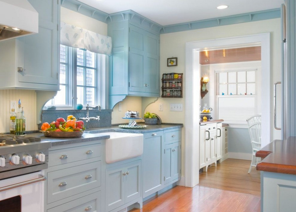 Inspiration for a mid-sized country galley eat-in kitchen in Other with a farmhouse sink, blue cabinets, soapstone benchtops, panelled appliances, light hardwood floors, recessed-panel cabinets, yellow splashback, timber splashback, no island and brown floor.
