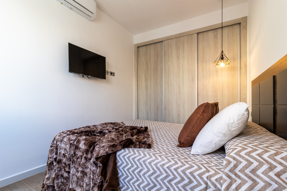 Foto de dormitorio blanco y madera urbano pequeño con paredes blancas, suelo de baldosas de porcelana y suelo marrón