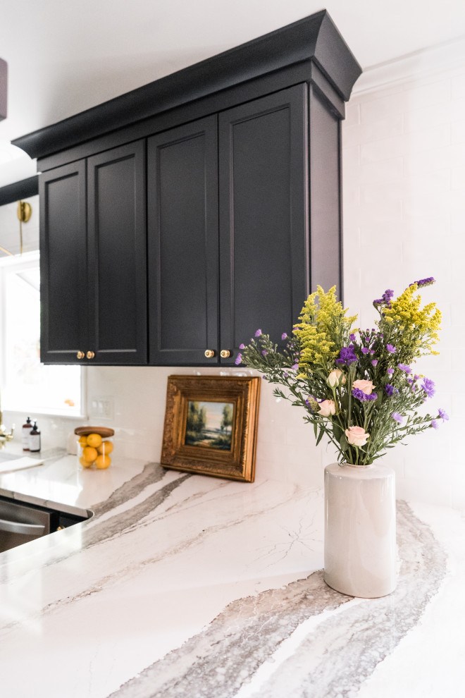 Example of a mid-sized transitional u-shaped laminate floor open concept kitchen design with a farmhouse sink, black cabinets, quartzite countertops, white backsplash and a peninsula