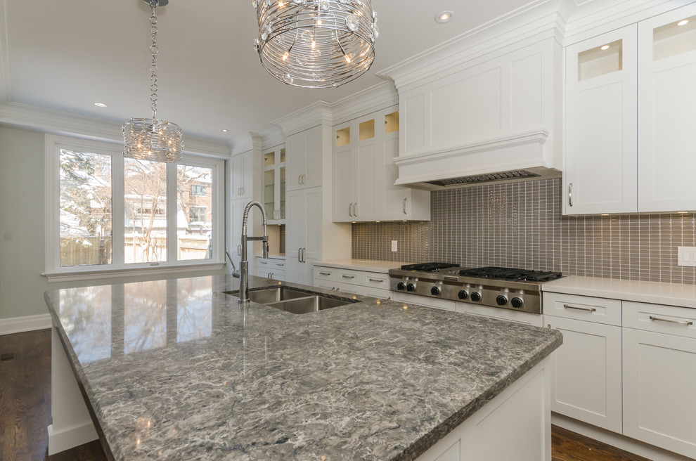 Mid-sized transitional u-shaped medium tone wood floor eat-in kitchen photo in Toronto with a double-bowl sink, raised-panel cabinets, white cabinets, granite countertops, gray backsplash, mosaic tile backsplash, stainless steel appliances and an island