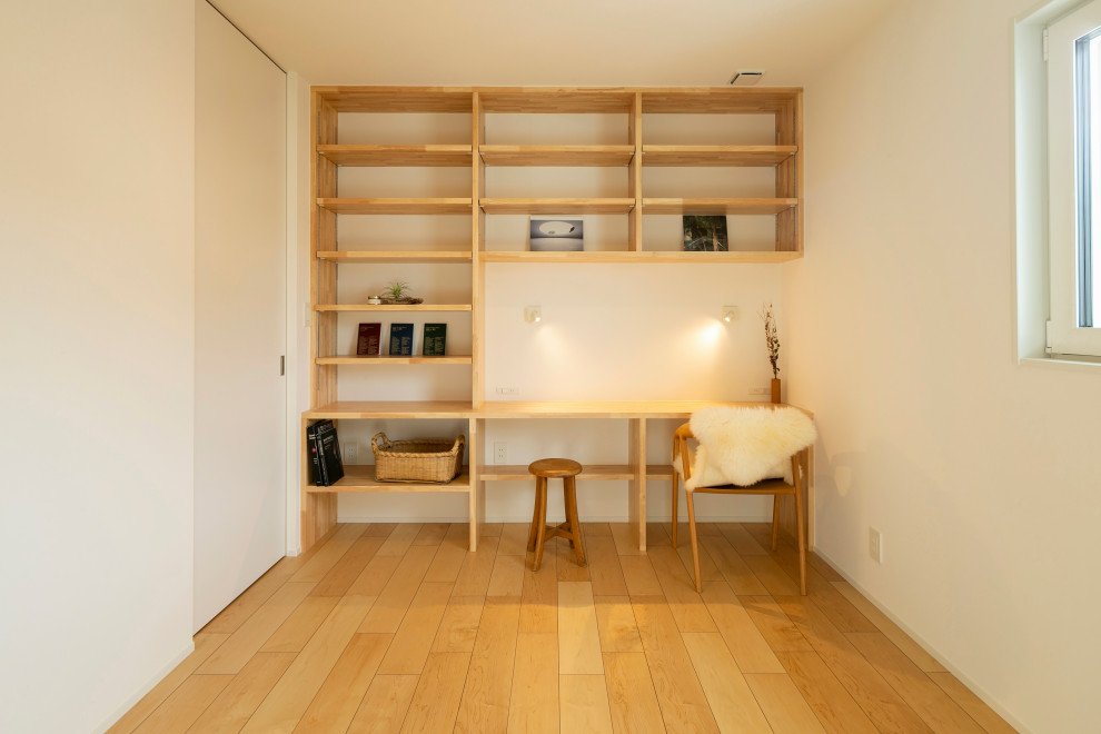 This is an example of a mid-sized scandinavian study room in Other with white walls, light hardwood floors, no fireplace, a built-in desk, beige floor, wallpaper and wallpaper.