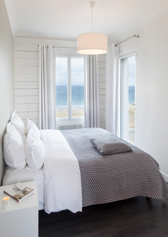 Example of a small beach style guest dark wood floor bedroom design in Other with white walls and no fireplace