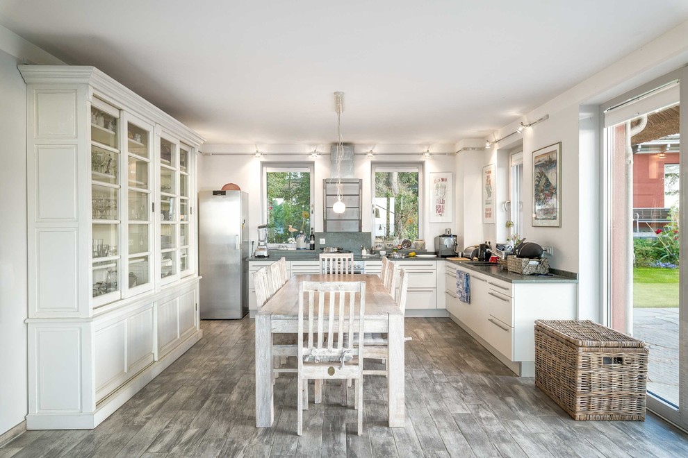 Inspiration for a large mediterranean u-shaped open plan kitchen in Other with flat-panel cabinets, white cabinets, stainless steel appliances, no island, beige floor and grey benchtop.