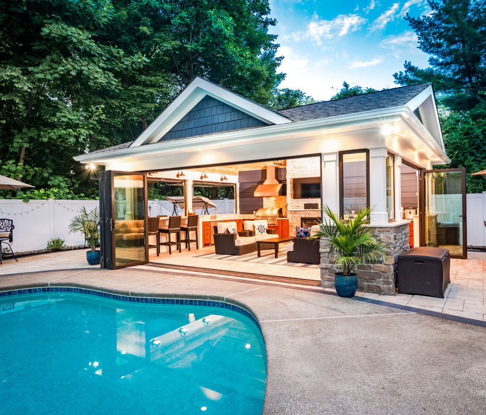 Photo of a mid-sized beach style backyard rectangular natural pool in New York with a pool house and concrete slab.