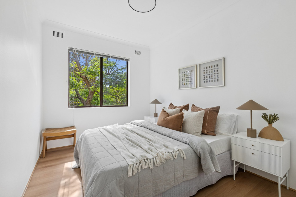 This is an example of a contemporary bedroom in Sydney with white walls, light hardwood floors and beige floor.