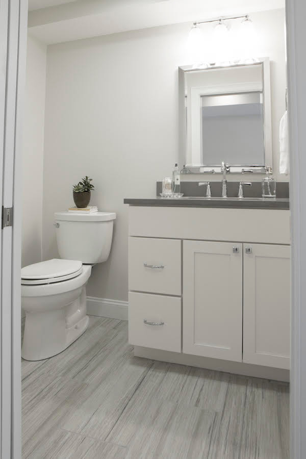 Small modern 3/4 bathroom in Providence with recessed-panel cabinets, white cabinets, a two-piece toilet, white walls, vinyl floors, a drop-in sink, engineered quartz benchtops and grey floor.
