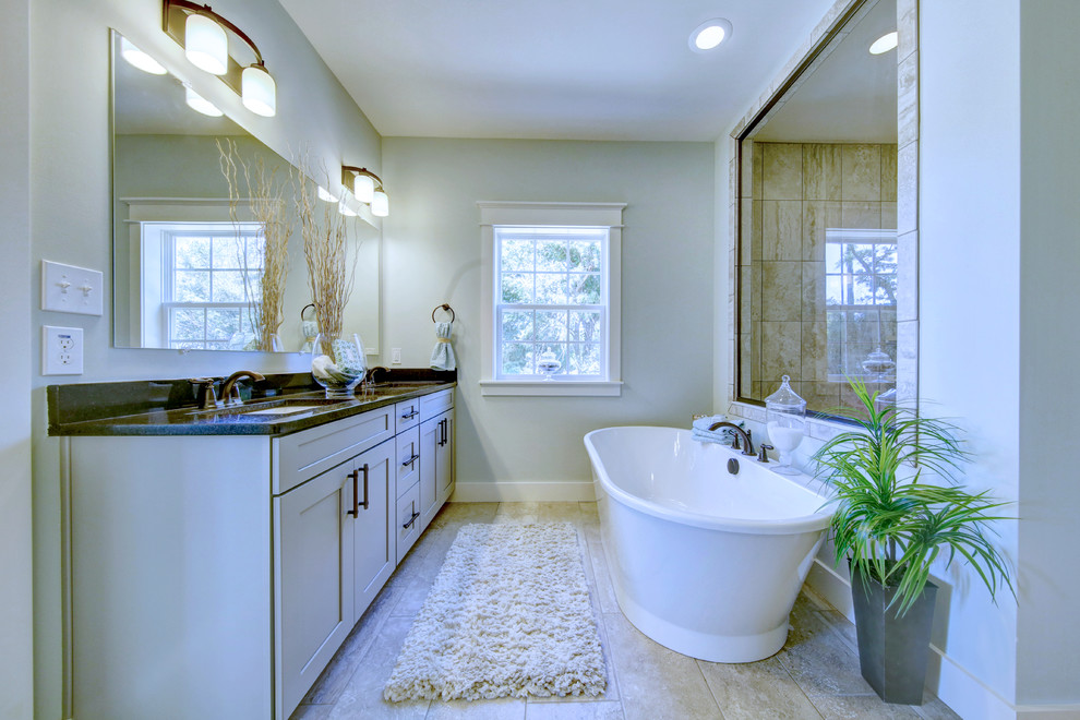 Photo of a mid-sized transitional master bathroom in Other with recessed-panel cabinets, grey cabinets, a freestanding tub, an open shower, a two-piece toilet, beige tile, ceramic tile, grey walls, ceramic floors, an undermount sink and granite benchtops.