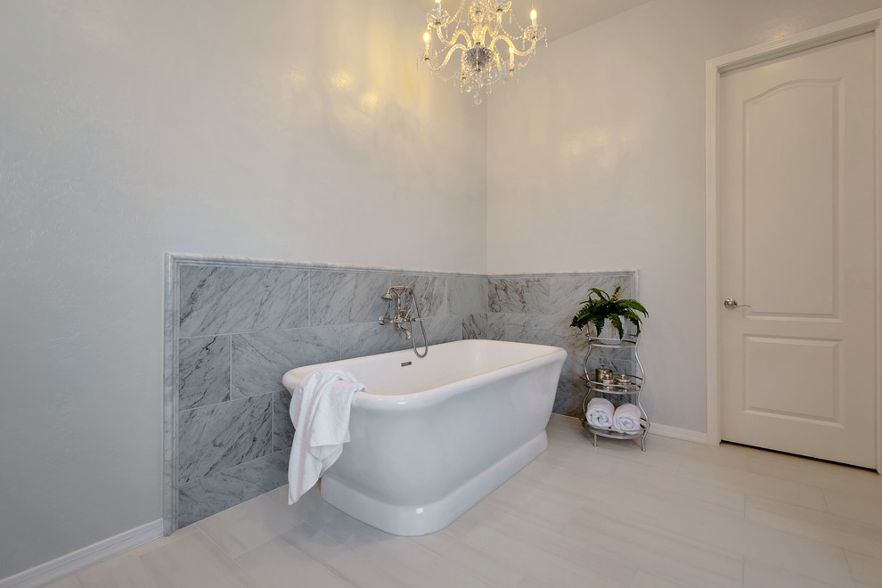 Large transitional master gray tile and marble tile porcelain tile and gray floor freestanding bathtub photo in Phoenix with recessed-panel cabinets, white cabinets, gray walls, a drop-in sink, quartz countertops and white countertops
