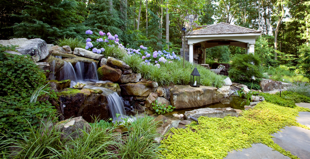 Waterfall that is man made empties from woodlands on a natural slope that was asking for a water display. The dream was created and we added the hydrangea and the yellow creeping jenny on the large fl