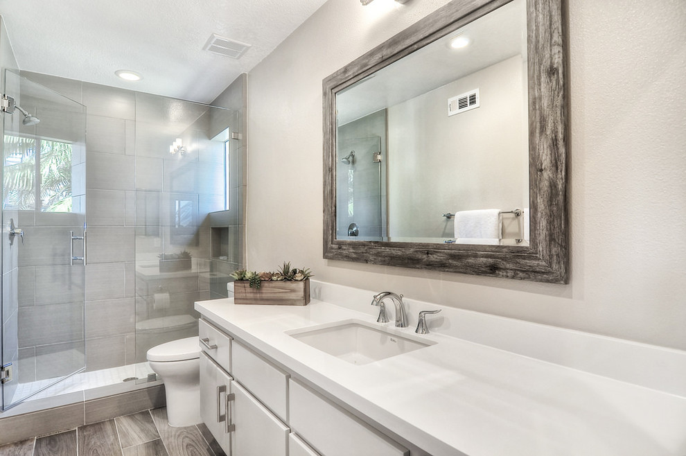 Photo of a large contemporary 3/4 bathroom in Orange County with an undermount sink, flat-panel cabinets, beige cabinets, engineered quartz benchtops, an alcove shower, a one-piece toilet, gray tile, porcelain tile, beige walls and porcelain floors.