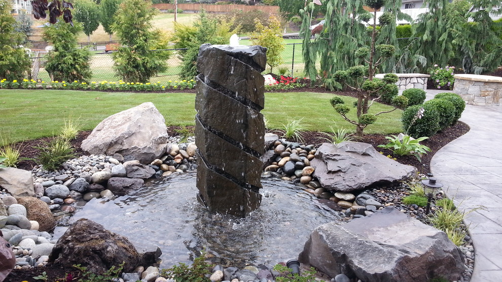 Photo of a large asian backyard formal garden in Portland with a water feature and natural stone pavers.
