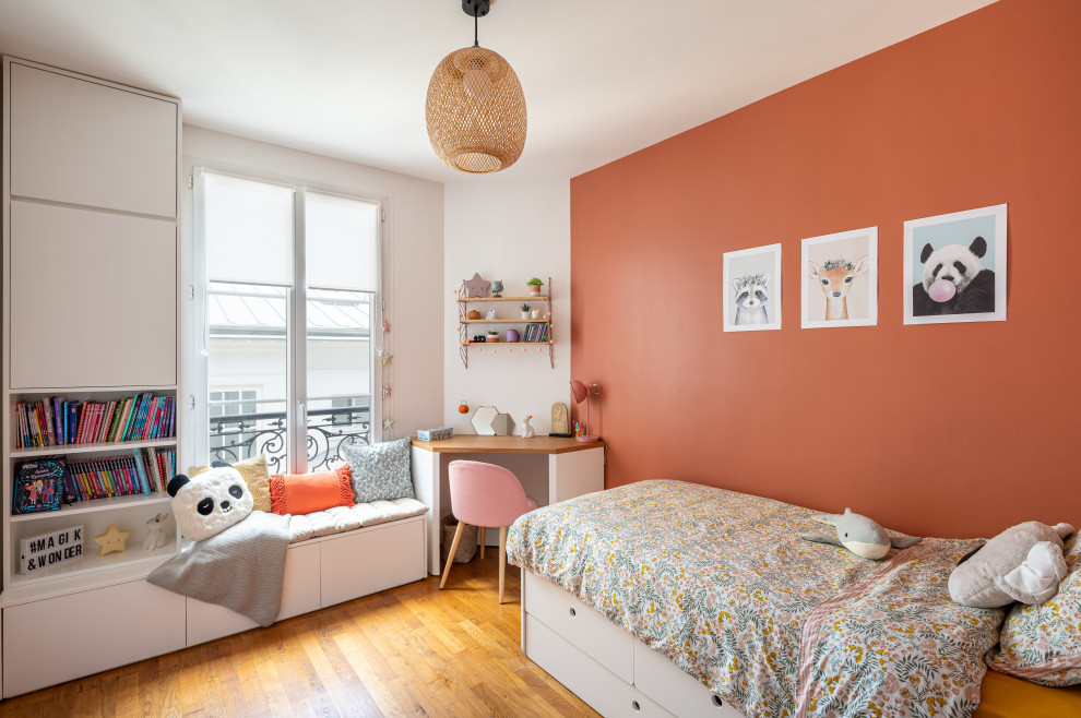 Ejemplo de dormitorio infantil de 4 a 10 años actual grande con paredes rojas y suelo de madera en tonos medios