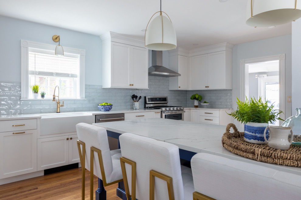 Bild på ett vintage vit vitt kök och matrum, med en rustik diskho, skåp i shakerstil, vita skåp, bänkskiva i kvarts, blått stänkskydd, stänkskydd i glaskakel, rostfria vitvaror, mellanmörkt trägolv, en köksö och brunt golv