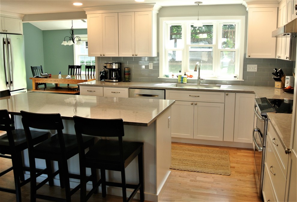 Inspiration for a transitional light wood floor kitchen remodel in Boston with an undermount sink, shaker cabinets, white cabinets, quartz countertops, gray backsplash, subway tile backsplash, stainless steel appliances, an island and gray countertops