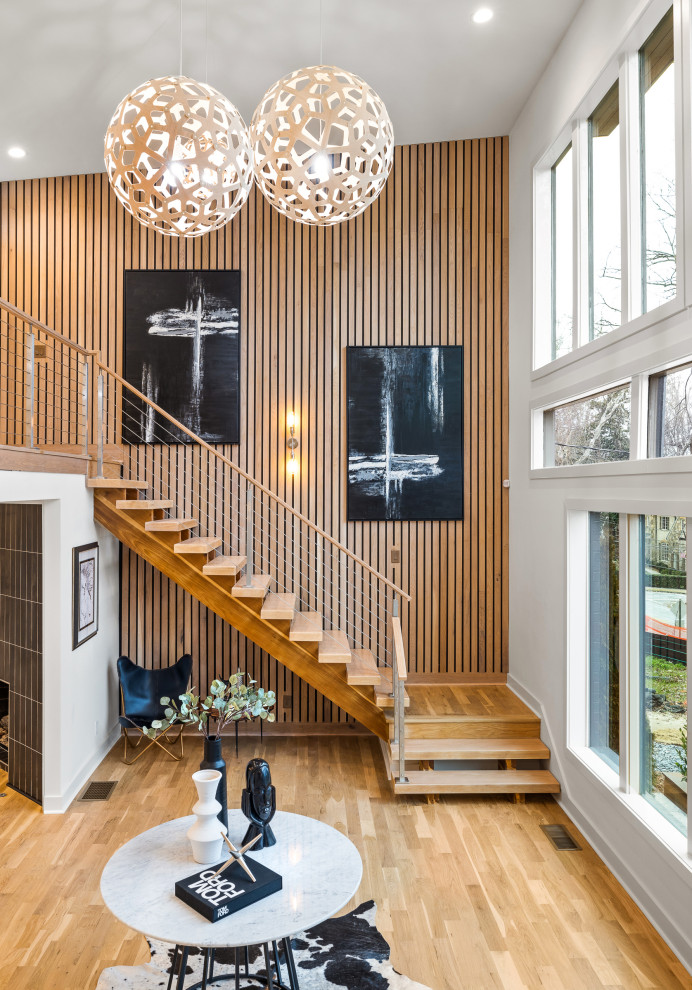 Photo of a large contemporary wood floating wire cable railing staircase in Atlanta with wood walls, open risers and a feature wall.