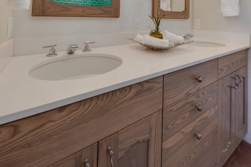 Design ideas for a mid-sized master bathroom in Albuquerque with an undermount sink, recessed-panel cabinets, medium wood cabinets, solid surface benchtops, a drop-in tub, white tile, white walls and ceramic floors.