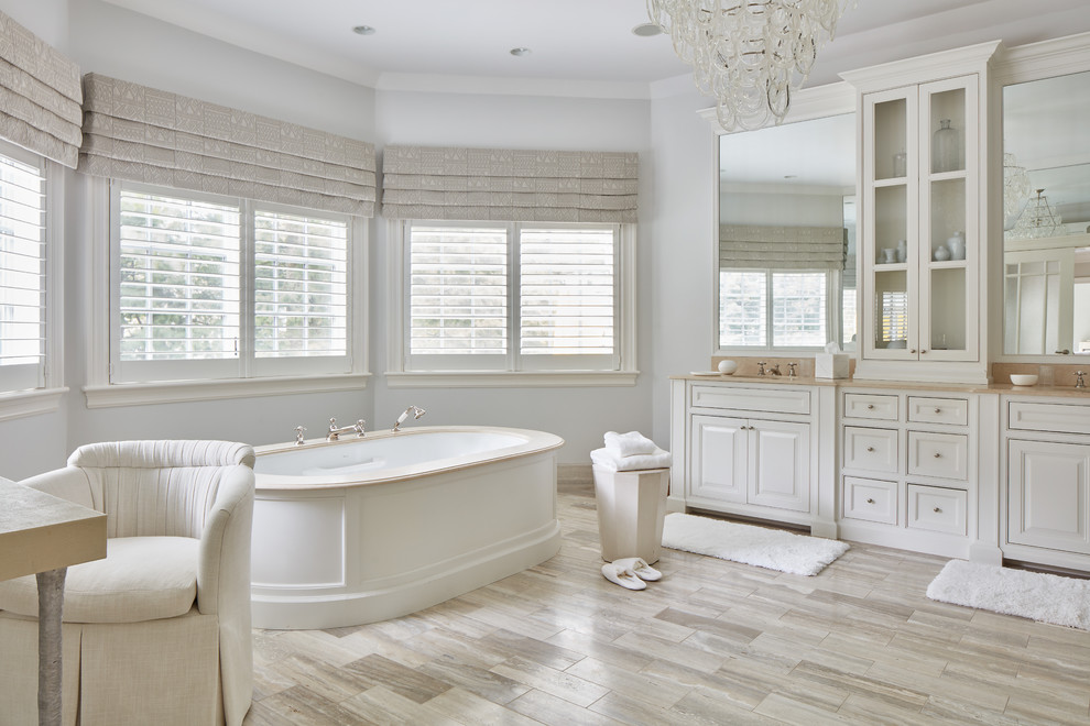 Design ideas for a traditional master bathroom in Boston with raised-panel cabinets, white cabinets, a freestanding tub, white walls and beige floor.