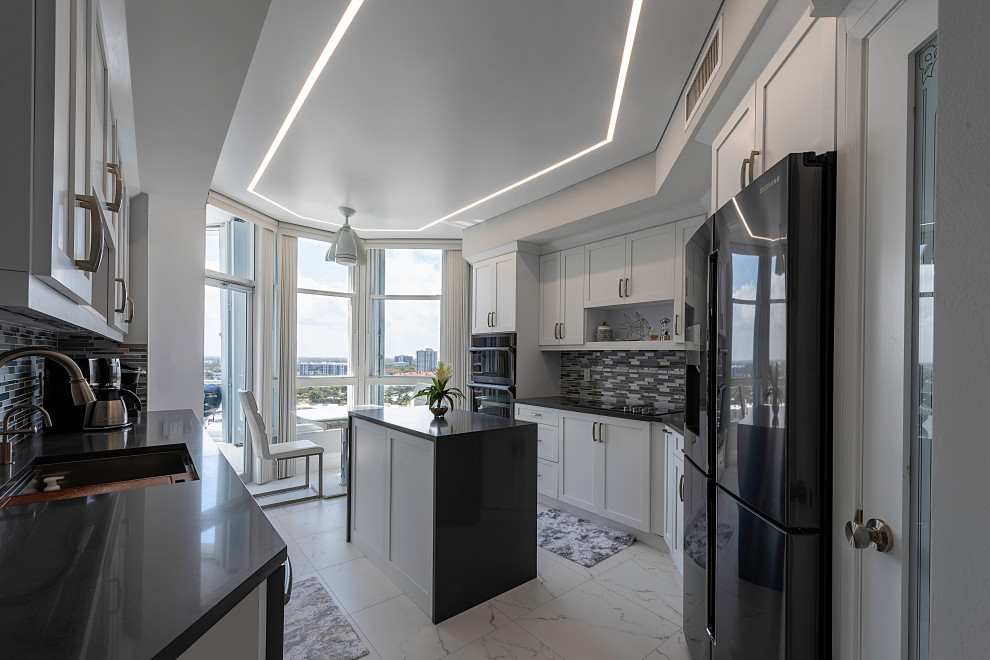 Photo of a mid-sized modern u-shaped separate kitchen in Miami with recessed-panel cabinets, white cabinets, with island, white floor, black benchtop, black appliances and wallpaper.