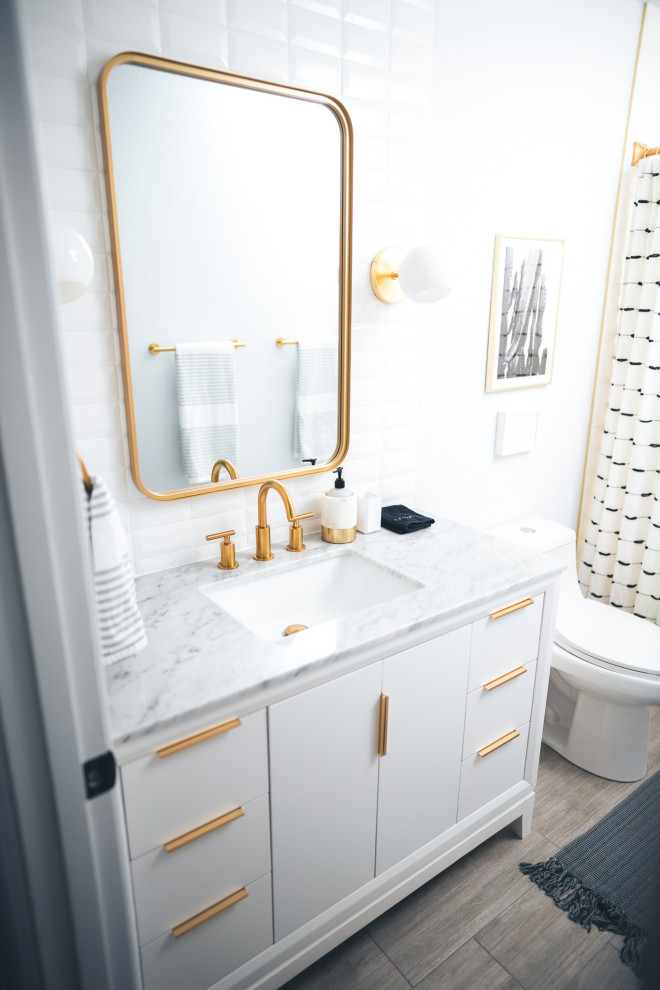 Inspiration för ett litet 60 tals vit vitt badrum med dusch, med släta luckor, vita skåp, ett badkar i en alkov, en dusch/badkar-kombination, en toalettstol med hel cisternkåpa, vit kakel, tunnelbanekakel, vita väggar, klinkergolv i porslin, ett undermonterad handfat, marmorbänkskiva, grått golv och dusch med duschdraperi