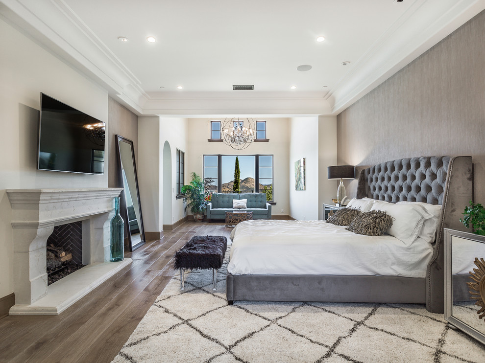 Design ideas for an expansive mediterranean master bedroom in San Francisco with grey walls, dark hardwood floors, a standard fireplace and brown floor.
