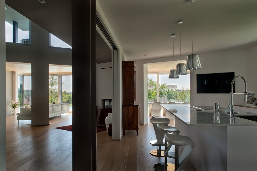 This is an example of a large contemporary galley open plan kitchen in Other with a submerged sink, marble worktops, stainless steel appliances, light hardwood flooring, an island and grey worktops.