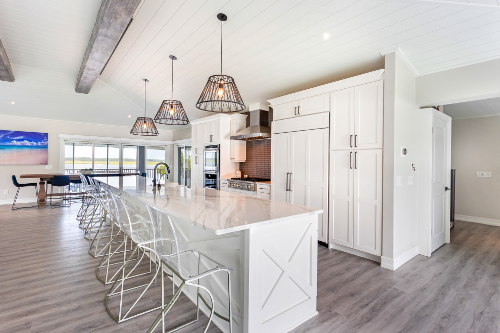 Design ideas for an expansive beach style single-wall eat-in kitchen in Jacksonville with a farmhouse sink, shaker cabinets, white cabinets, quartz benchtops, black splashback, glass sheet splashback, stainless steel appliances, vinyl floors, with island, multi-coloured floor, multi-coloured benchtop and exposed beam.