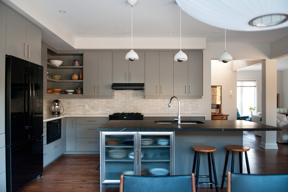 Photo of a contemporary kitchen in Toronto with black appliances, flat-panel cabinets, grey cabinets, soapstone benchtops, white splashback and matchstick tile splashback.