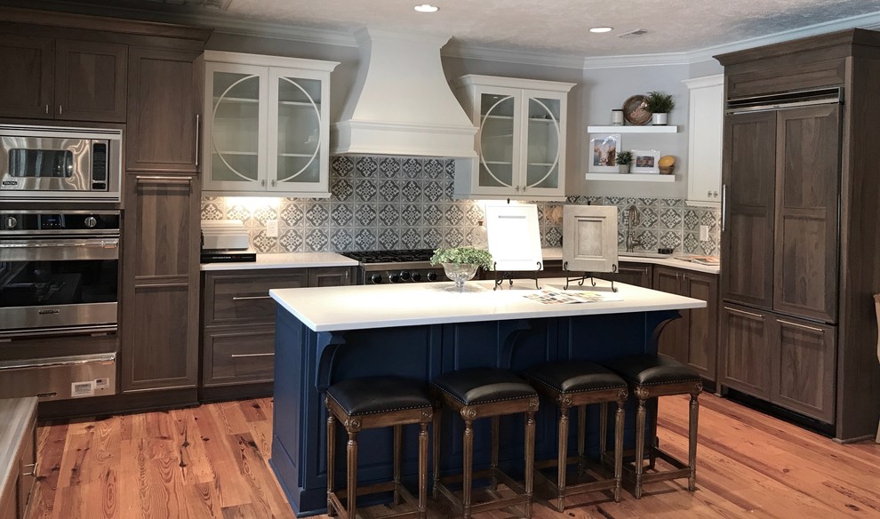 Large country l-shaped eat-in kitchen in Raleigh with an undermount sink, shaker cabinets, quartz benchtops, cement tile splashback, stainless steel appliances, medium hardwood floors, with island and brown floor.