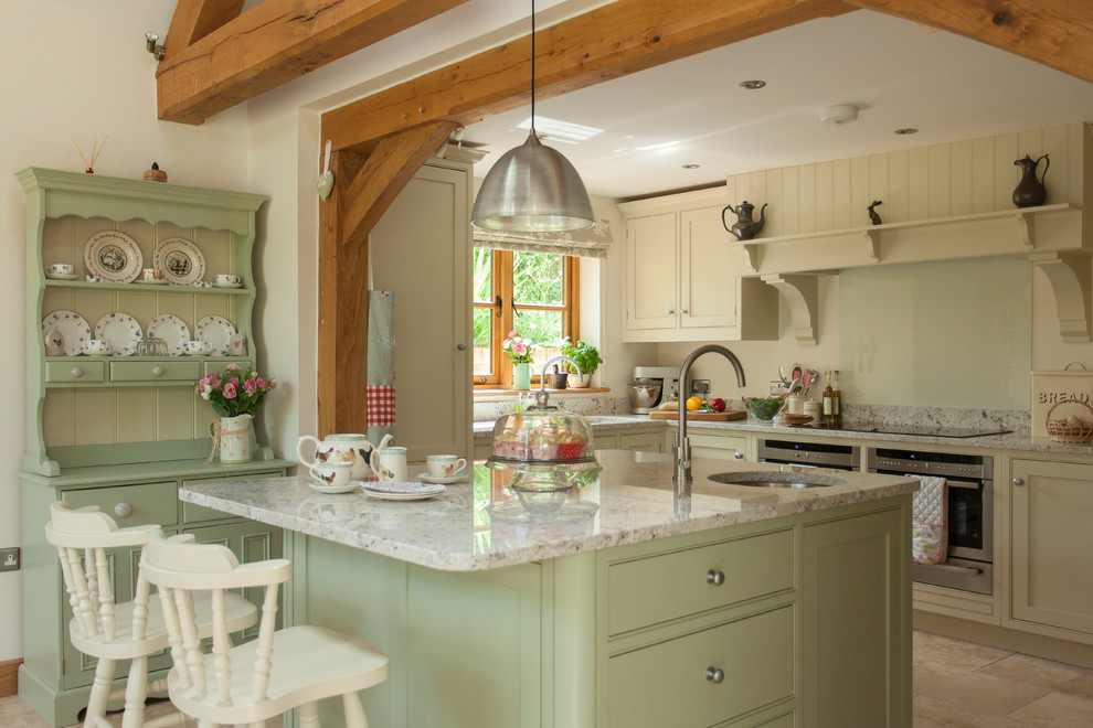 Design ideas for a large traditional l-shaped eat-in kitchen in Gloucestershire with a drop-in sink, shaker cabinets, green cabinets, granite benchtops, white splashback, glass sheet splashback, stainless steel appliances, travertine floors, with island, beige floor and green benchtop.