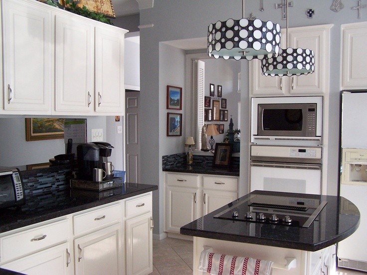 This is an example of a small country u-shaped separate kitchen in Kansas City with raised-panel cabinets, white cabinets, granite benchtops, black splashback, mosaic tile splashback, stainless steel appliances, porcelain floors and with island.