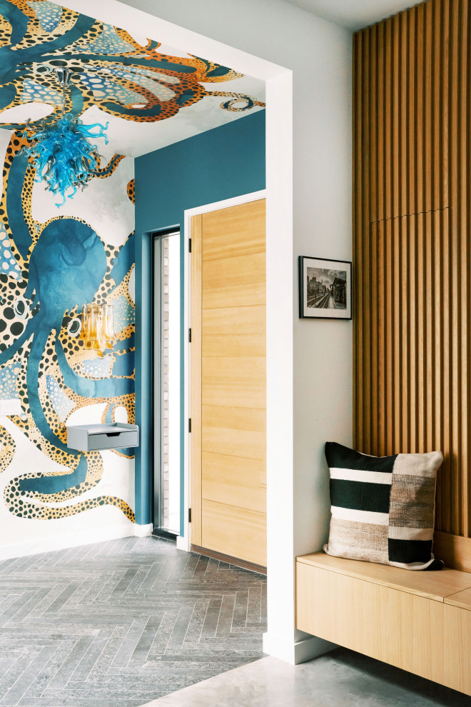 オースティンにあるトランジショナルスタイルのおしゃれな玄関ロビー (青い壁、淡色木目調のドア、グレーの床、板張り壁) の写真