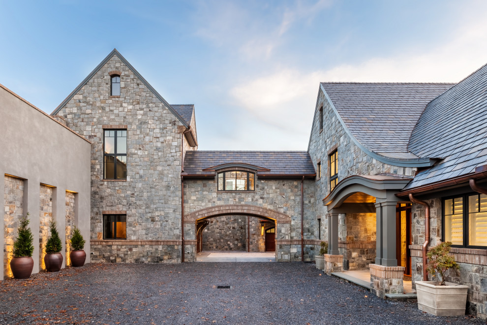 Стильный дизайн: большой, двухэтажный, серый частный загородный дом в стиле неоклассика (современная классика) с облицовкой из камня, двускатной крышей, черепичной крышей и серой крышей - последний тренд