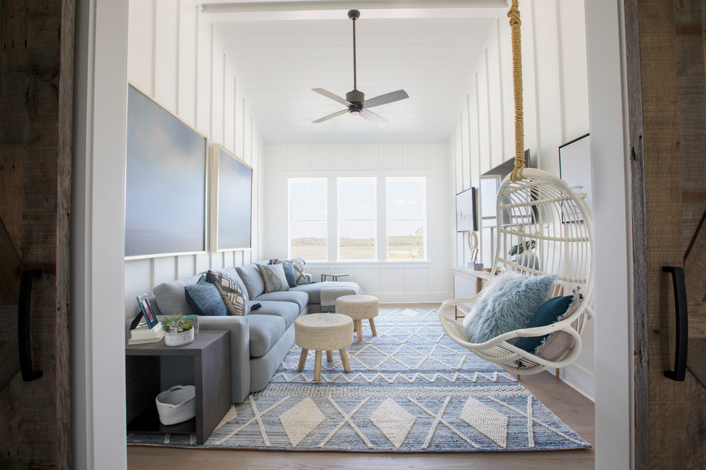 Example of a beach style enclosed dark wood floor and brown floor family room design in Charleston with white walls and a wall-mounted tv