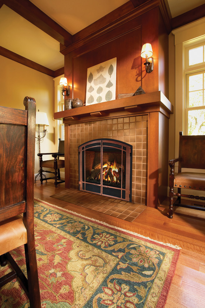 Large arts and crafts separate dining room in Denver with yellow walls, medium hardwood floors, a standard fireplace, a tile fireplace surround and brown floor.