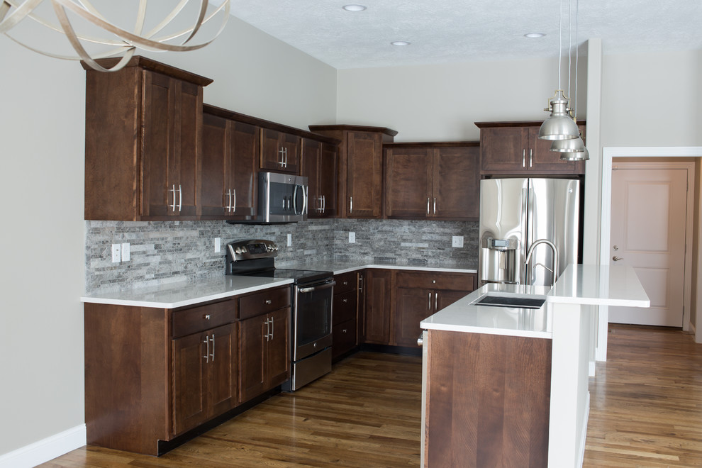Enclosed kitchen - mid-sized transitional l-shaped dark wood floor enclosed kitchen idea with a double-bowl sink, shaker cabinets, dark wood cabinets, quartz countertops, gray backsplash, stone tile backsplash, stainless steel appliances and an island