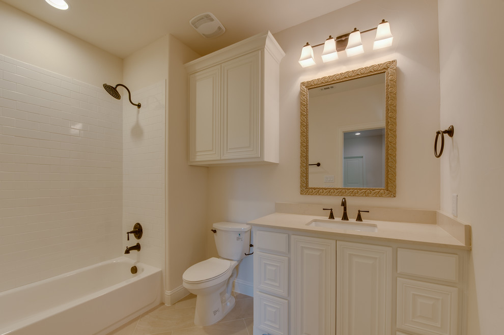 Mid-sized mediterranean kids bathroom in Dallas with an undermount sink, white cabinets, granite benchtops, a drop-in tub, a shower/bathtub combo, a one-piece toilet, beige tile, terra-cotta tile, white walls and porcelain floors.