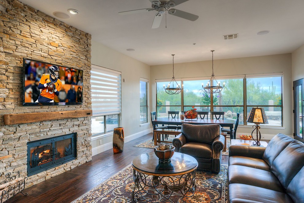 This is an example of a mid-sized contemporary open concept family room in Phoenix with beige walls, medium hardwood floors, a standard fireplace, a stone fireplace surround, a wall-mounted tv and brown floor.
