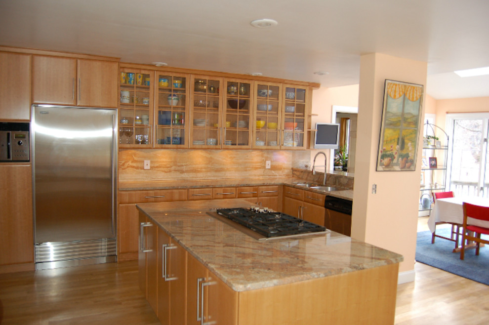 Example of a light wood floor kitchen design with flat-panel cabinets, light wood cabinets, stainless steel appliances and an island