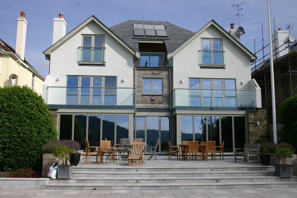 This is an example of an expansive contemporary three-storey stucco white exterior in Devon with a gable roof.