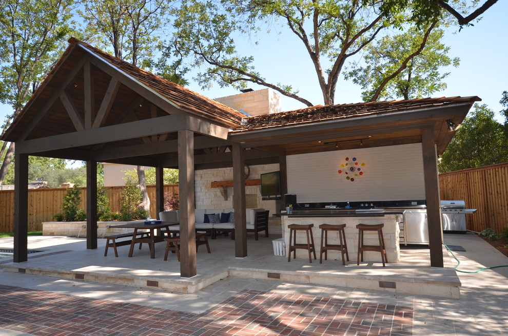 This is an example of a mid-sized arts and crafts backyard patio in Austin with an outdoor kitchen, concrete pavers and a pergola.