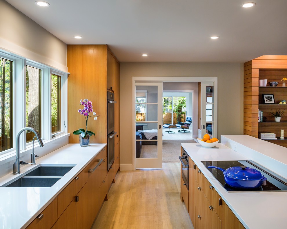 This is an example of a large transitional u-shaped eat-in kitchen in Austin with a double-bowl sink, flat-panel cabinets, medium wood cabinets, quartz benchtops, stainless steel appliances, light hardwood floors, with island and beige floor.