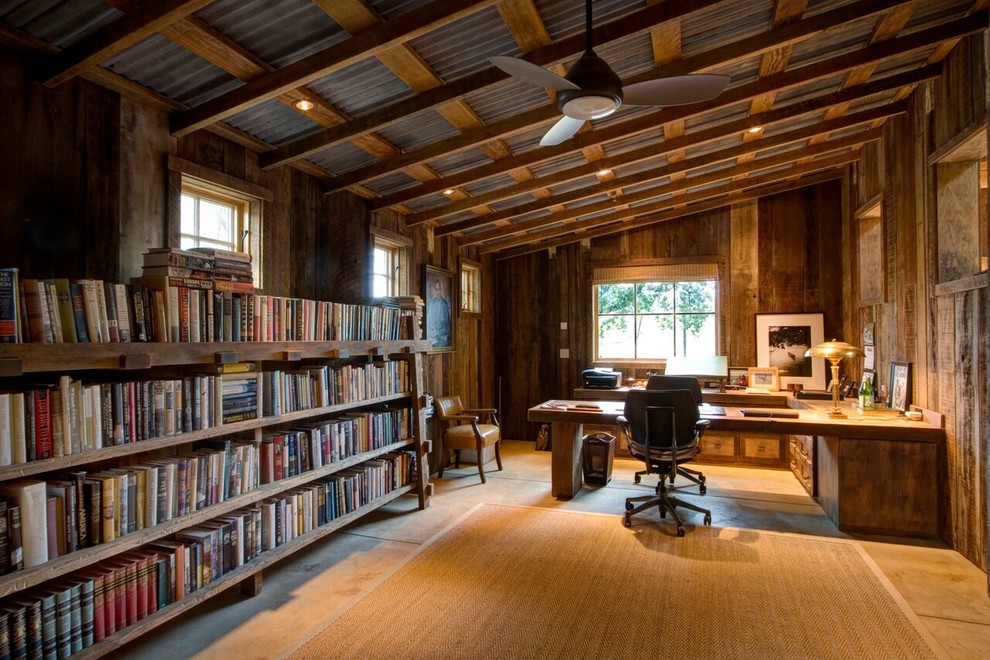This is an example of a mid-sized country home office in San Francisco with brown walls, concrete floors, a built-in desk, no fireplace, a library and grey floor.